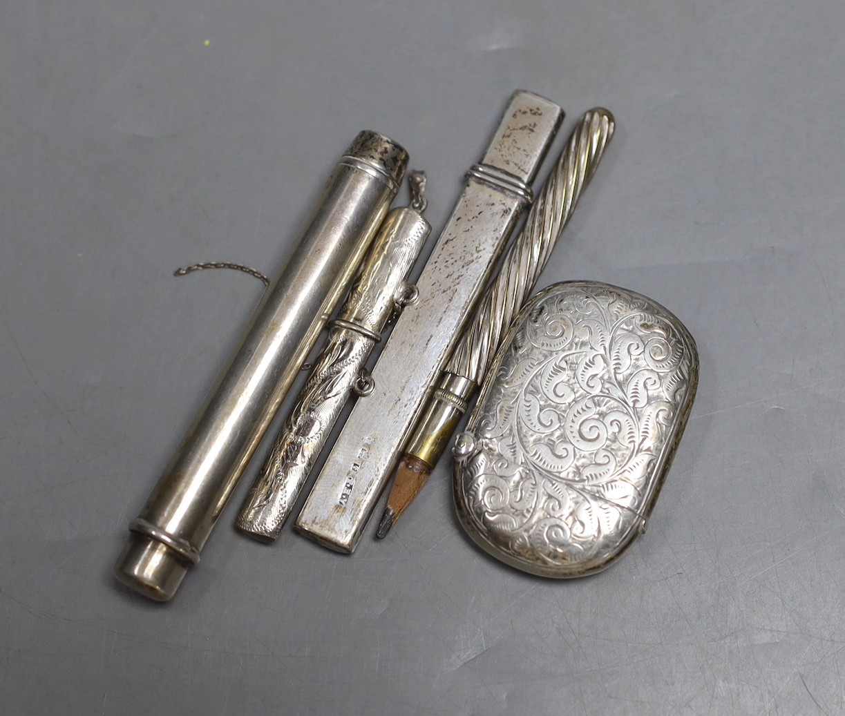 A silver vesta case, two silver pencil holders, one other plated holder and a white metal toothpick holder.